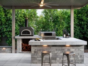 covered paved outdoor kitchen area with oven and grill