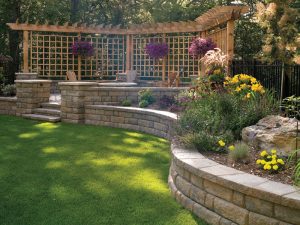 stone work on a retaining wall surrounding a well manicured green area and a patio with fire pit